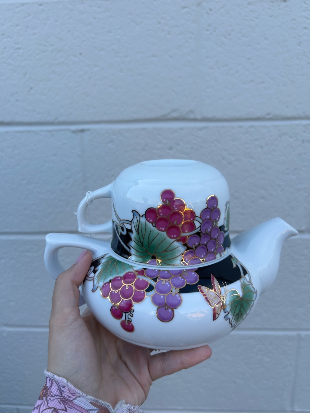 white porcelain teapot featuring a decorative purple grape cluster, green leaves